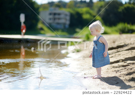 Adorable girl throwing stones into river 22924422