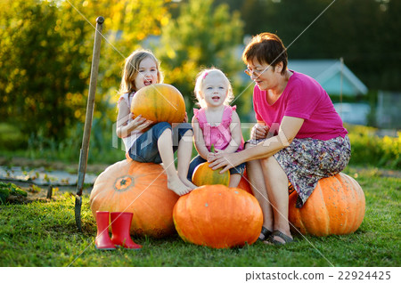 Two little sisters sitting on a huge pumpkins 22924425