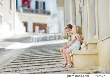 Two adorable little sisters laughing and hugging Two adorable little sisters laughing and hugging 22925249