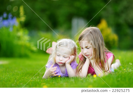 Two cute little sisters having fun on the grass Two cute little sisters having fun on the grass 22925275