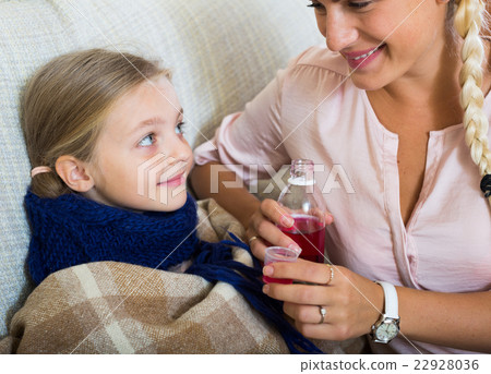 Unwell little girl taking mixture from worried mother Unwell little girl taking mixture from worried mother 22928036