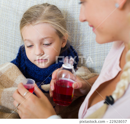 Stressed woman giving liquid medicine to little girl with grippe Stressed woman giving liquid medicine to little girl with grippe 22928037