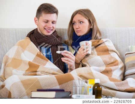 Sick couple under blanket checking fever Sick couple under blanket checking fever 22928705