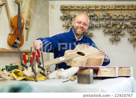Craftsman holding unfinished guitar 22928767
