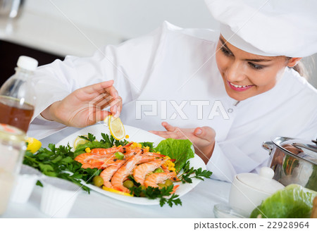 Young chef arranging shrimps on plate 22928964