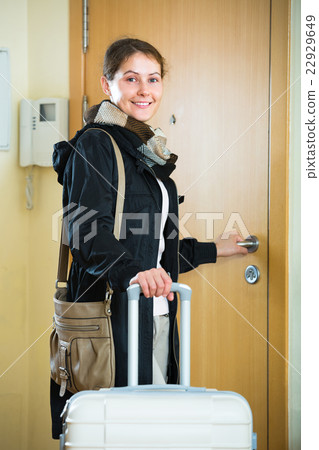 Adult brunette with baggage at the door. 22929649