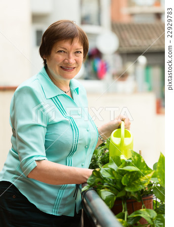 Portrait of happy woman watering domestic plants 22929783