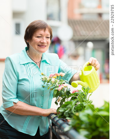 Elderly woman with watering-can taking care of plants Elderly woman with watering-can taking care of plants 22929785