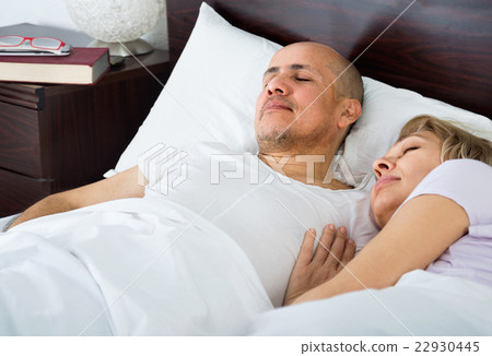 Portrait of ordinary mature couple napping in bed 22930445