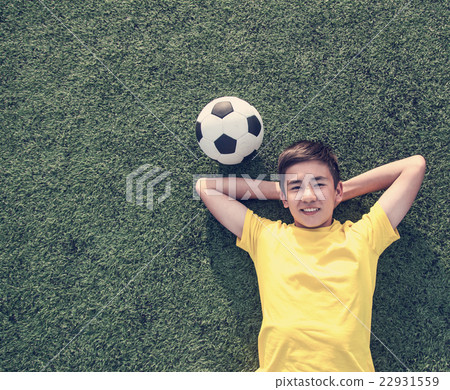 boy with a soccer ball lying on the green lawn boy with a soccer ball lying on the green lawn 22931559