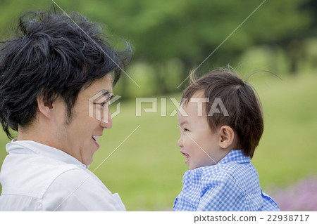 A boy laughing while staring at his father in the park 22938717