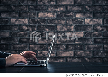 Male hand operating laptop dark room brick wall Male hand operating laptop dark room brick wall 22945128