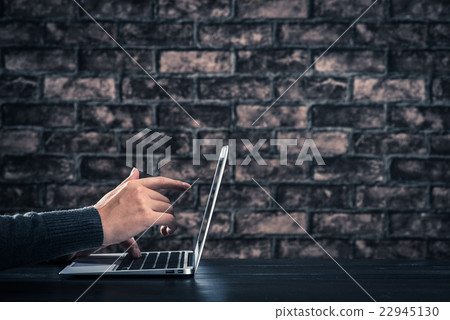 Male hand operating laptop dark room brick wall Male hand operating laptop dark room brick wall 22945130