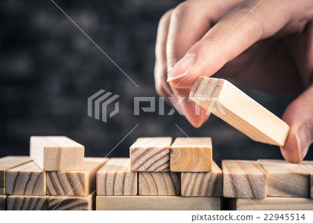 A hand stacking wooden blocks 22945514