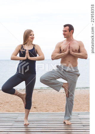 Man and pregnant woman are doing yoga on the beach 22958358