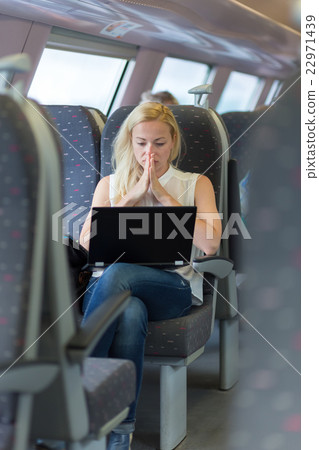 Woman travelling by train working on laptop. 22971439