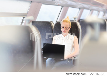 Woman travelling by train working on laptop. 22976133