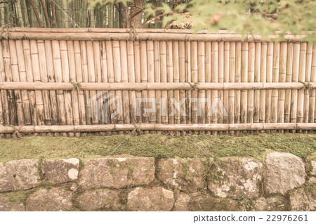 Bamboo fence on stone with green leaves . ( Filtered image processed vintage effect. ) 22976261