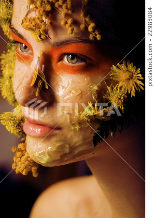 young woman with yellow floral mask on her face young woman with yellow floral mask on her face 22983084