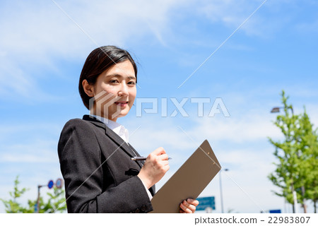 A woman from a young office worker who checks with a clipboard with blue sky behind A woman from a young office worker who checks with a clipboard with blue sky behind 22983807