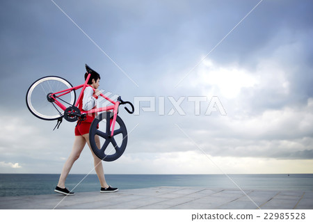 Young girl stroll with bicycle at seashore Young girl stroll with bicycle at seashore 22985528
