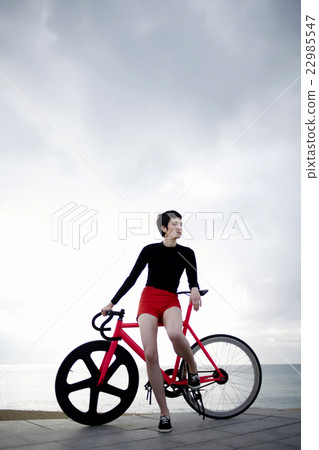 Stylish cyclist female standing against the sky Stylish cyclist female standing against the sky 22985547
