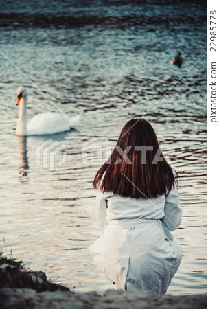 brunette in a white cloak and swan in water 22985778