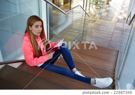 Girl resting after classes sitting on the stairs Girl resting after classes sitting on the stairs 22987169