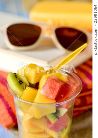 fruit salad, sunglasses, book and beach towel 22991064