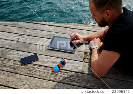 Man student reading digital e-book on touchpad Man student reading digital e-book on touchpad 22996541