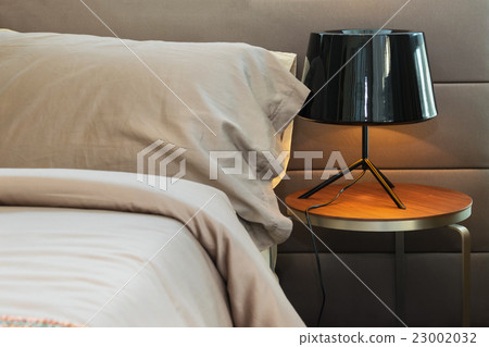 modern black lamp and brown pillow on bed 23002032