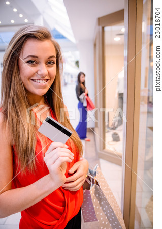 Portrait of happy woman showing her credit card outside a shop Portrait of happy woman showing her credit card outside a shop 23018704