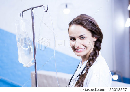 Portrait of female doctor carrying saline stand 23018857