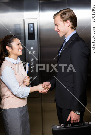 Businessman shaking hands with businesswoman in elevator Businessman shaking hands with businesswoman in elevator 23018953