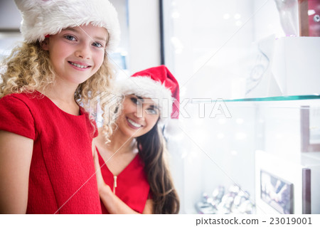 Mother and daughter in Christmas attire smiling in a shop 23019001