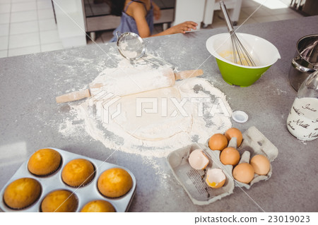 Rolling pin on dough with muffins and egg at kitchen table 23019023