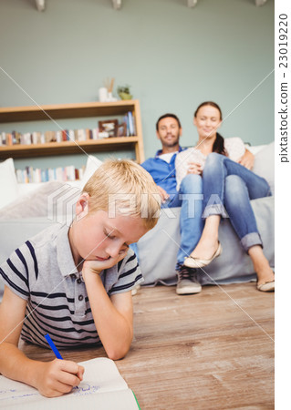Boy drawing on book while parents looking at him Boy drawing on book while parents looking at him 23019220