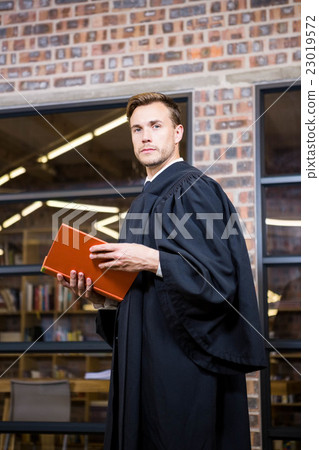 Lawyer standing near library with law book 23019572