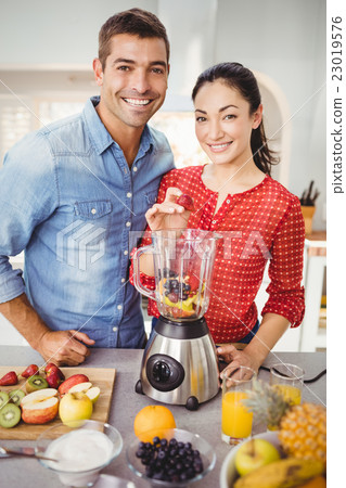 Portrait of smiling couple preparing fruit juice Portrait of smiling couple preparing fruit juice 23019576