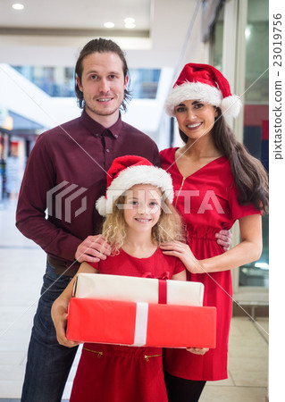 Family in Christmas attire standing with Christmas gifts Family in Christmas attire standing with Christmas gifts 23019756
