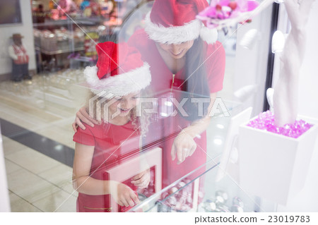 Mother and daughter in Christmas attire looking at wrist watch d Mother and daughter in Christmas attire looking at wrist watch d 23019783