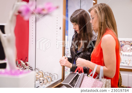 Two beautiful women looking at a display in shop Two beautiful women looking at a display in shop 23019784