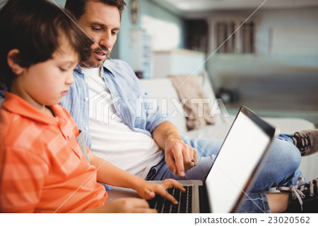 Father and son working on laptop while sitting on sofa Father and son working on laptop while sitting on sofa 23020562
