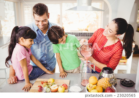 Happy family with mother pouring fruit juice in jug Happy family with mother pouring fruit juice in jug 23020565