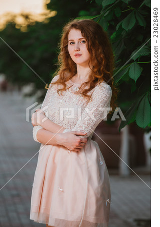 Beautiful girl in a pink dress posing in a  garden 23028469