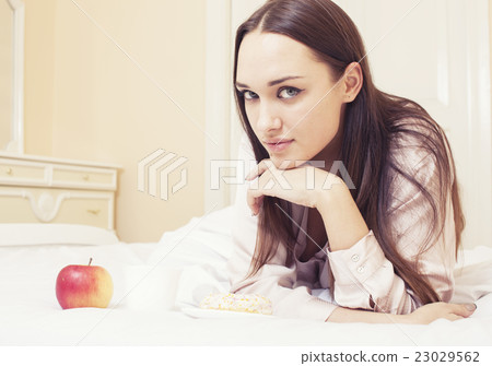 young pretty brunette woman laying in bed, luxury 23029562