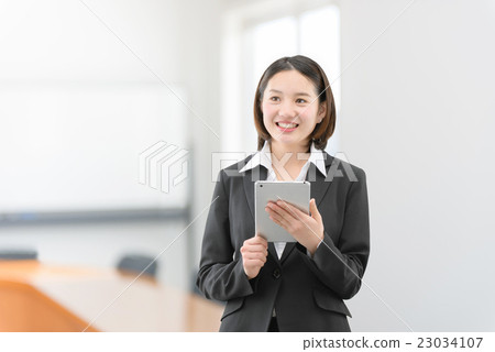 A woman in her twenties standing with a tablet in the office car A woman in her twenties standing with a tablet in the office car 23034107