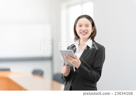 A woman in her twenties standing with a tablet in the office car A woman in her twenties standing with a tablet in the office car 23034108