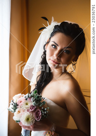 beautiful young happy bride standing near window beautiful young happy bride standing near window 23036791