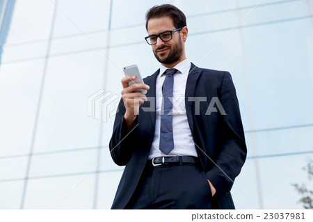 Young male economist is using cell telephone Young male economist is using cell telephone 23037981